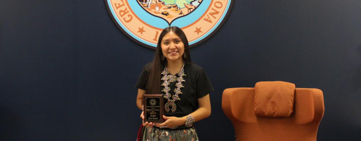 Markayla Shirley, one of the October students of the month holding her award and standing in front of the Arizona State seal