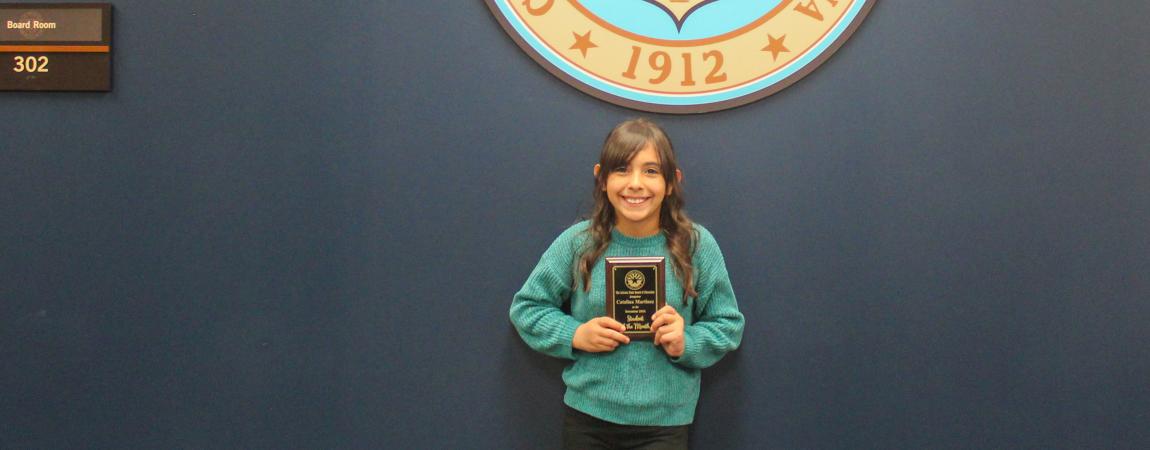 Catalina Martinez, one of the December 2024 Students of the Month, standing in front of the Arizona State Seal